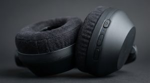 Macro view of a black headphone earcup highlighting the padded cushion and buttons.