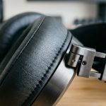 Premium matte black over ear headphones sitting on a minimalist studio display stand.