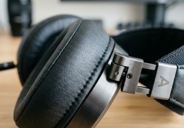 Premium matte black over ear headphones sitting on a minimalist studio display stand.