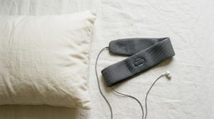 Close up of ultra thin sleep headphones flat on a white pillow.
